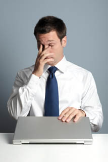 Businessman at laptop, rubbing his dry eyes
